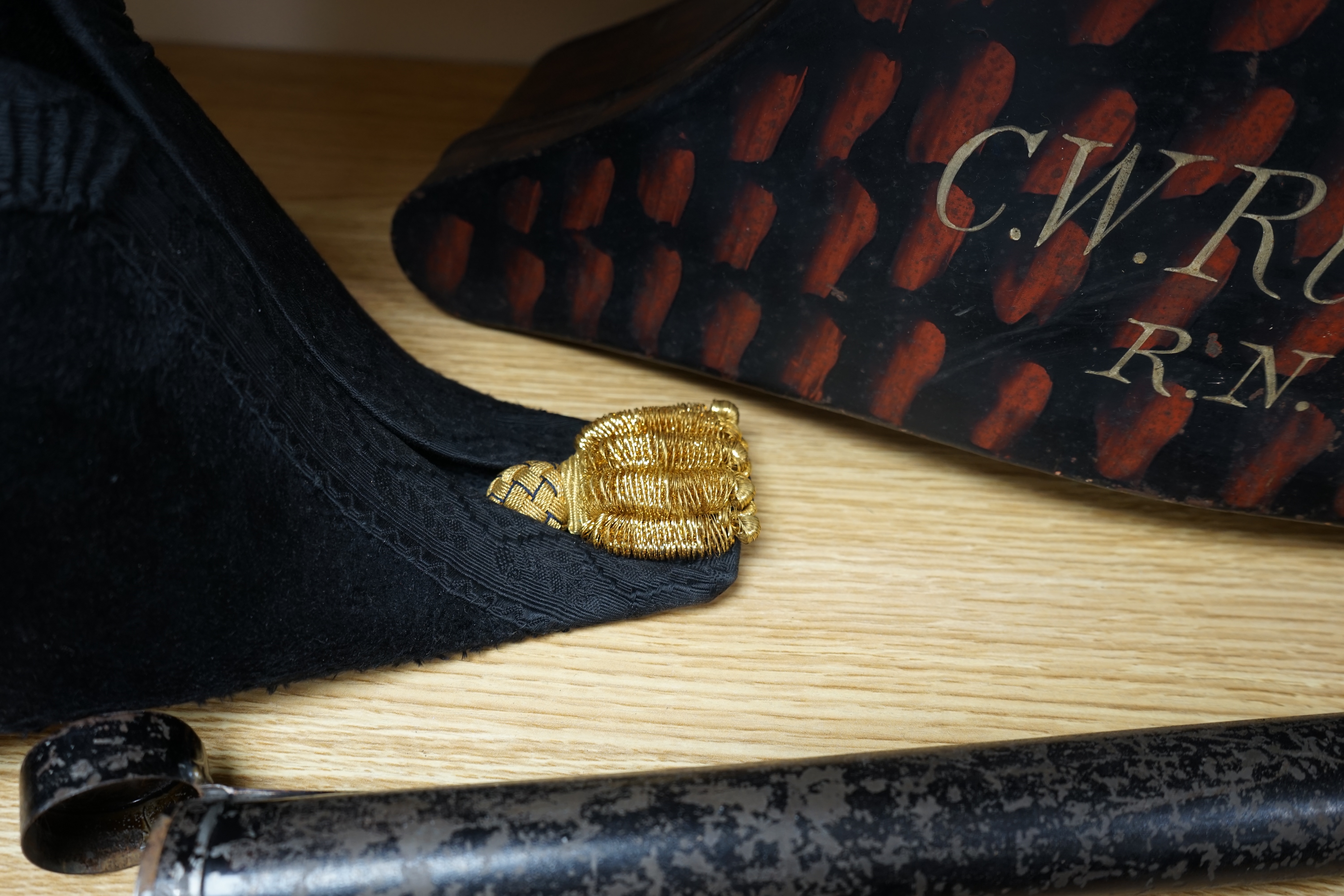 A bicorn hat and tin box, the latter inscribed C.W.Ruse, R.N, together with a black single Plume, in a double ended tin box and a red and white Plume by Hawkes of London, in a double ended tin box (3). Condition - fair t